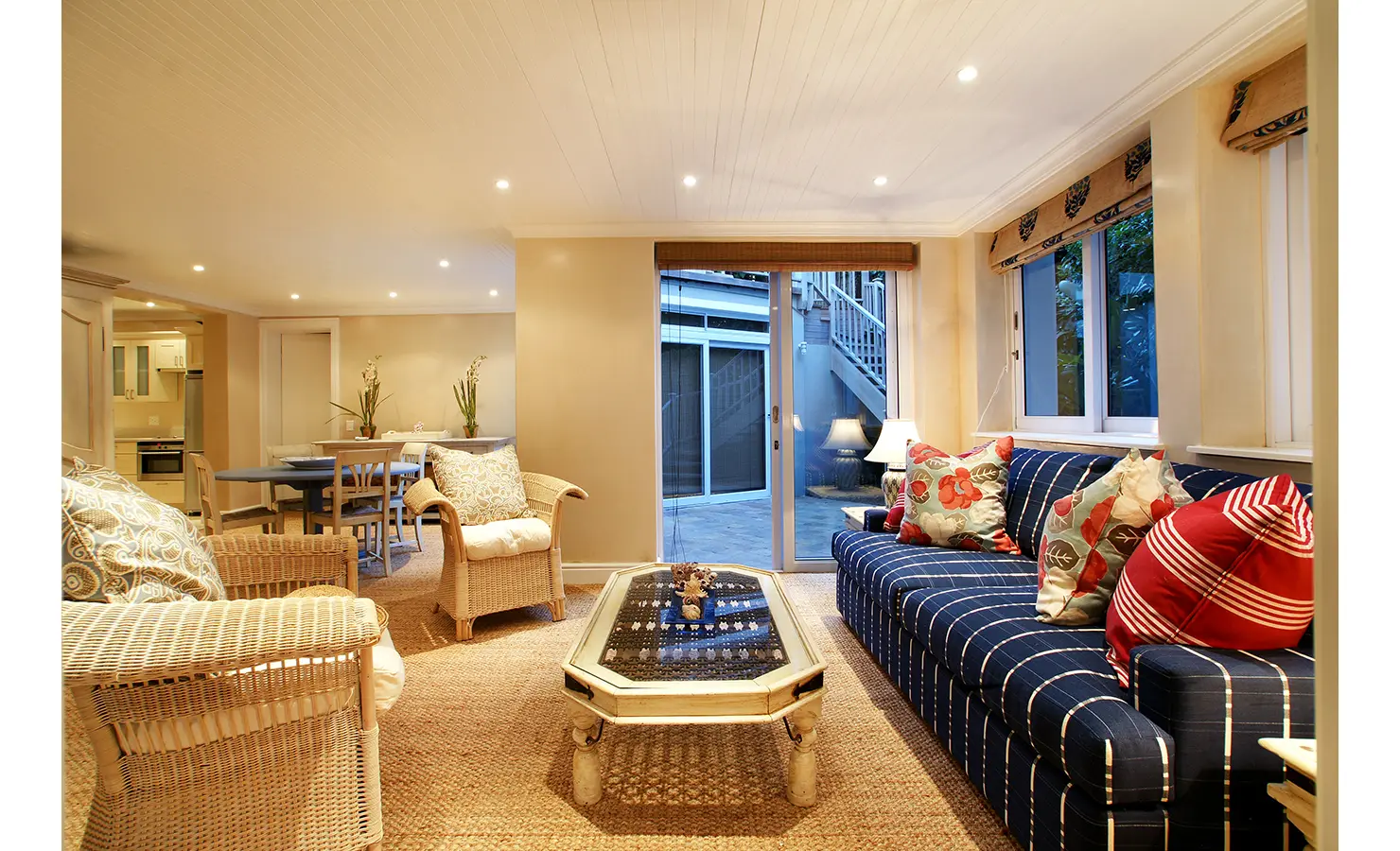 Perfect Hideaways: A charming country-style dining area with a rustic wooden table, soft natural lighting, and a view of the garden and pool through classic French doors. Dolphin Cottage, Camps Bay.