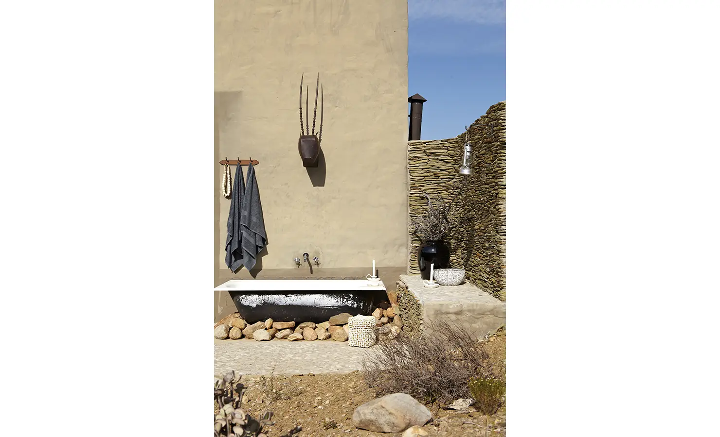 Perfect Hideaways: A rustic outdoor bath set against a stone and plaster wall is framed by natural rock and indigenous flora, perfect for starlit soaks in the wild. Stoney Cottage, Touwsberg Private Game and Nature Reserve.