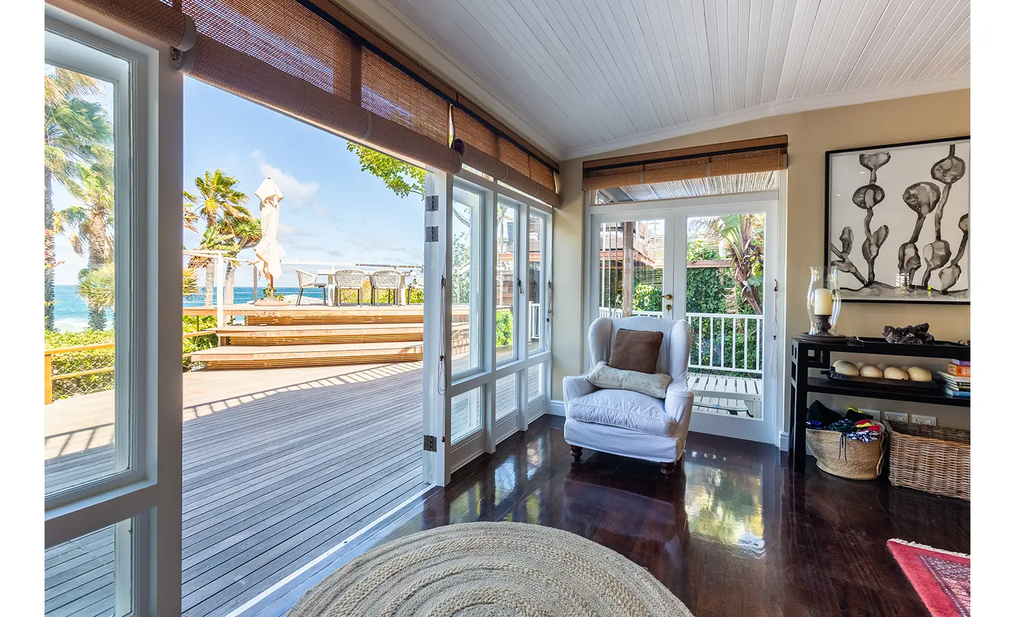 Perfect Hideaways: A sophisticated living room with plush seating, deep red and neutral tones, a fireplace, and elegant décor that combines African influences with classic comfort. Dolphin Cottage, Camps Bay.