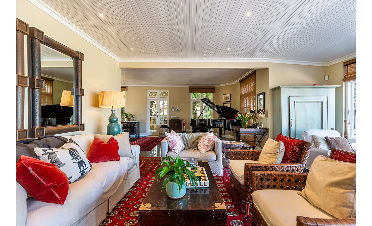 Perfect Hideaways: A sunlit indoor lounge opening onto a wooden deck with ocean views, seamlessly blending indoor and outdoor living for a perfect coastal escape. Dolphin Cottage, Camps Bay.