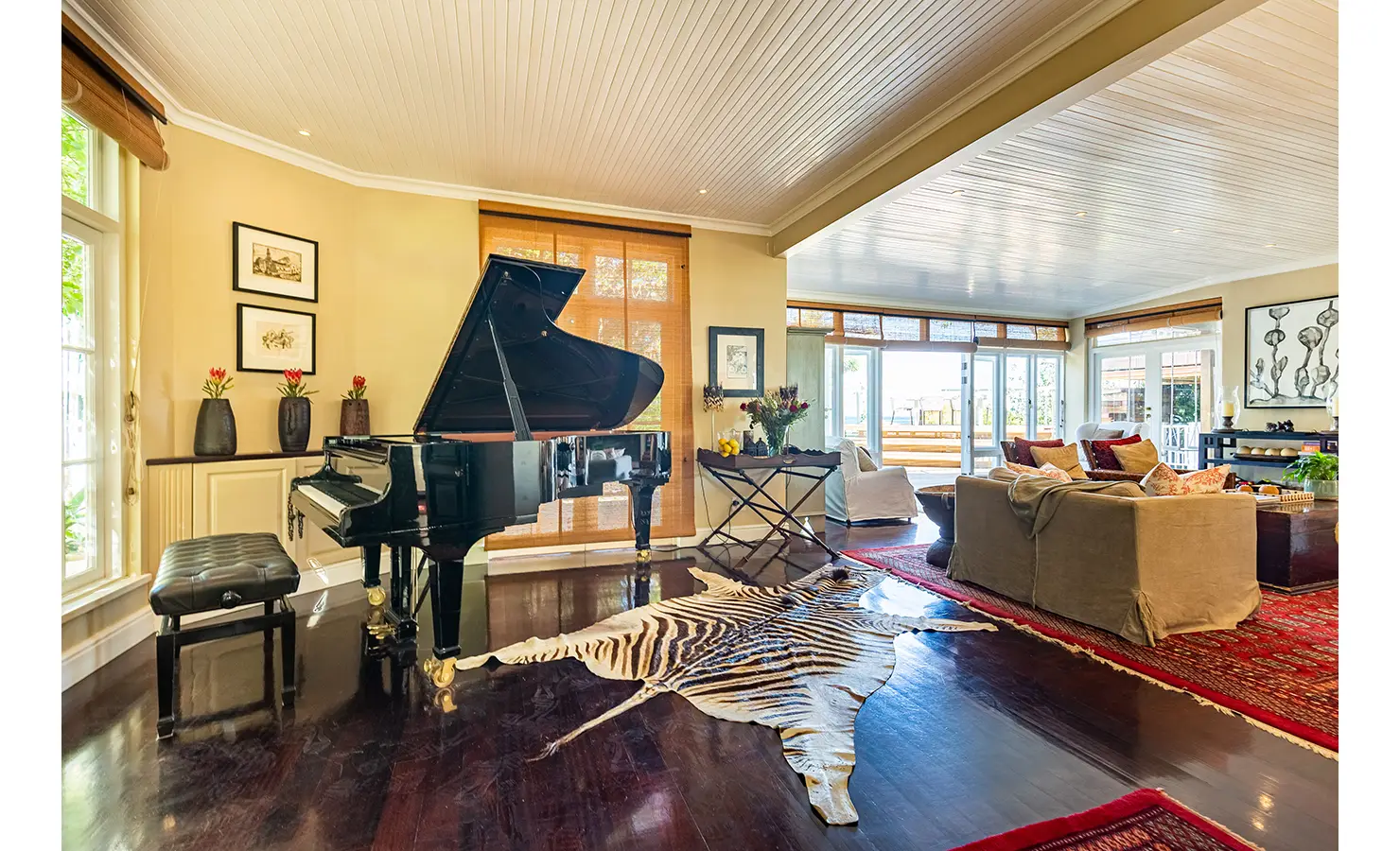 Perfect Hideaways: A spacious, stylish living area with a grand piano, woven armchairs, and rich textures, creating a refined yet relaxed ambience. Dolphin Cottage, Camps Bay.