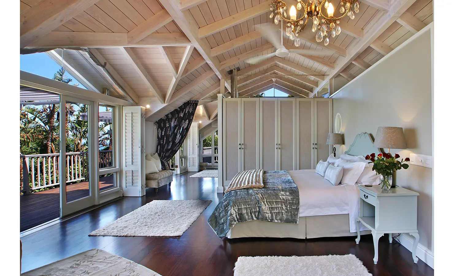 Perfect Hideaways: A spacious master suite with a chandelier, built-in wardrobes, and a cosy seating area, seamlessly blending comfort and coastal charm. Dolphin Cottage, Camps Bay.