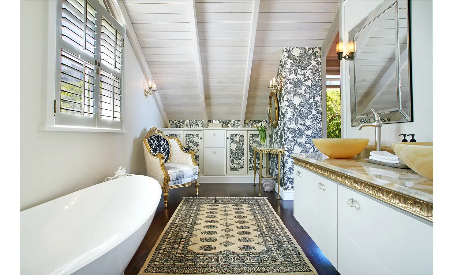 Perfect Hideaways: A luxurious bathroom with intricate floral wallpaper, a vintage-style chair, and opulent golden details, adding a regal touch to this serene sanctuary. Dolphin Cottage, Camps Bay.