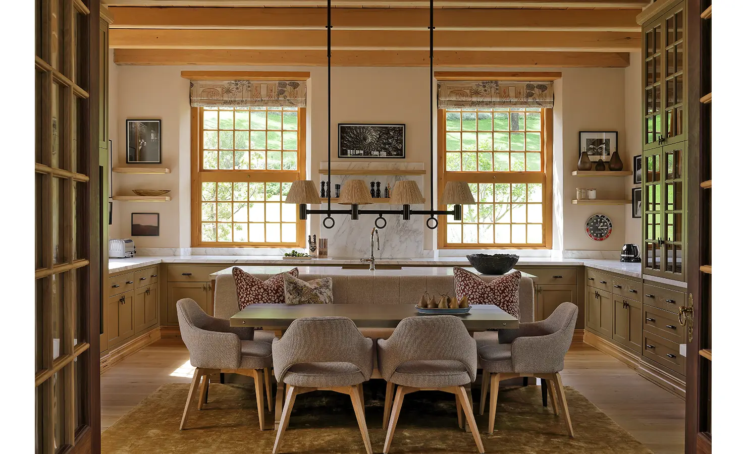 Perfect Hideaways: A dreamy open-plan kitchen and dining area with olive-green cabinetry, marble countertops, and soft, warm lighting, perfectly complementing the scenic vineyard views beyond the windows. Owloon, Paarl.
