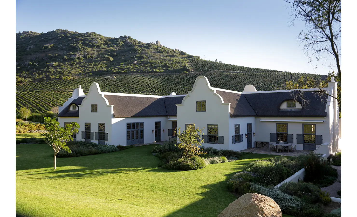 Perfect Hideaways: A breathtaking estate set against a dramatic mountain backdrop, with sprawling vineyards and a beautifully manicured lawn. Owloon, Paarl.