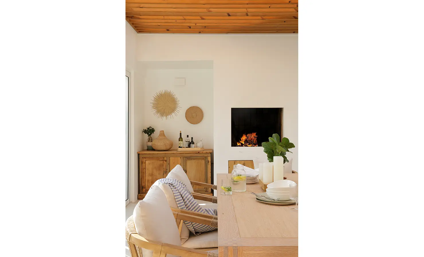 Perfect Hideaways: A stylish dining setting with light wood furniture and a glowing fireplace brings warmth to this open-plan space. Kinsail Beach Villa, Langebaan.