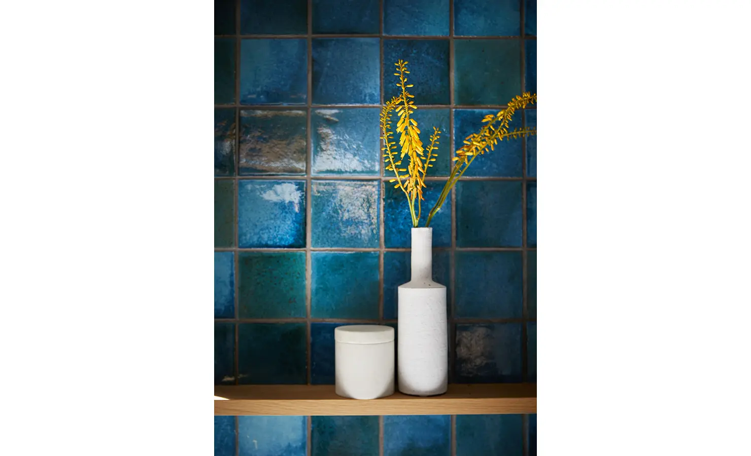 Bright blue and green tiles, white vases with yellow flowers. Cliffside. Hermanus.