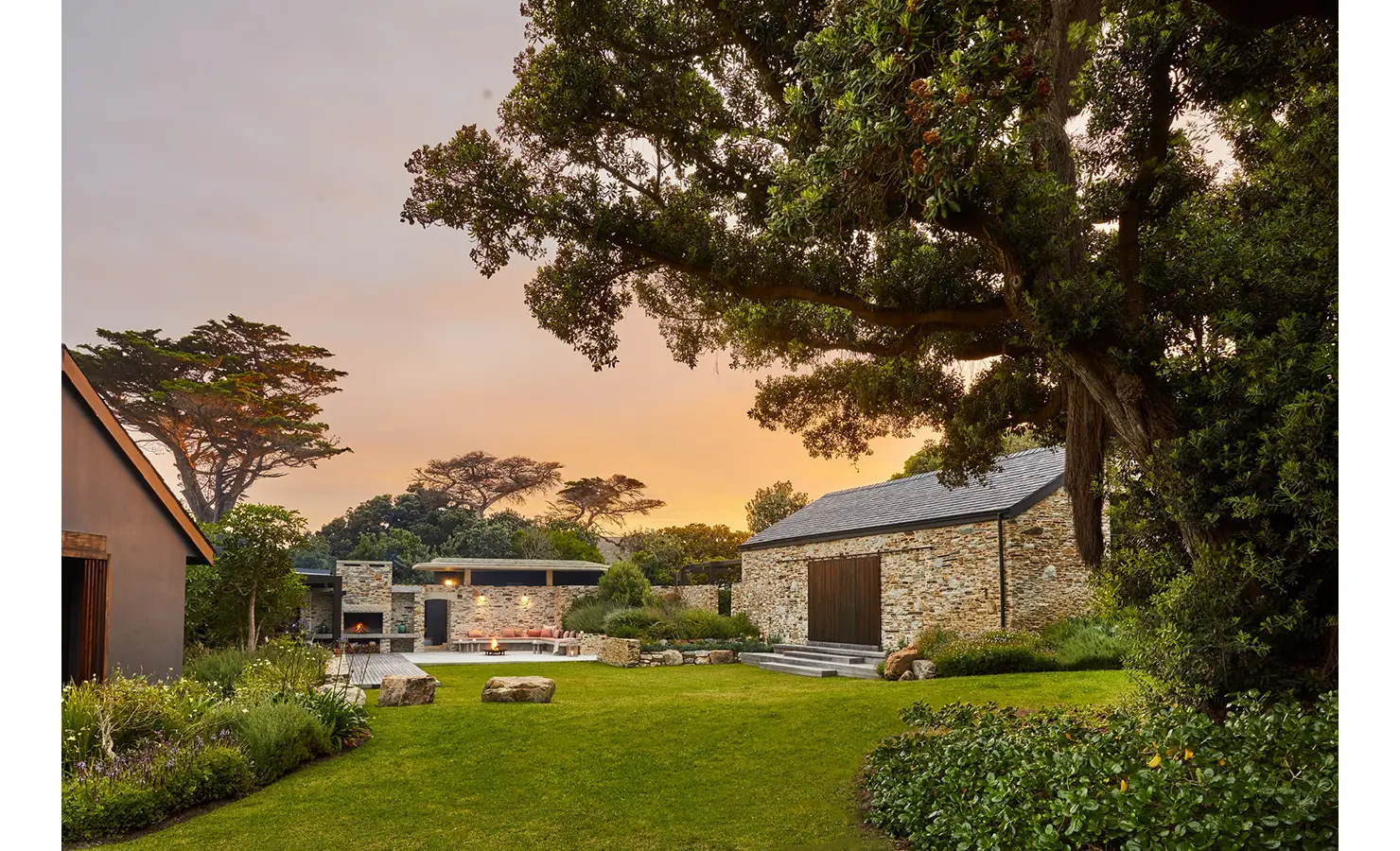 Garden with large tree, sunset backdrop and stone walled Cliffside. Hermanus.