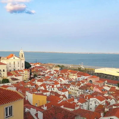 Colourful cluster of historic buildings in Lisbon with views of the ocean.