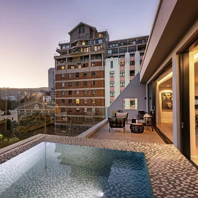 Top-floor presidential suite at Labotessa Hotel with large stack back doors that open the living area onto a deck with a mosaic plunge pool with views of the city and Lions Head.