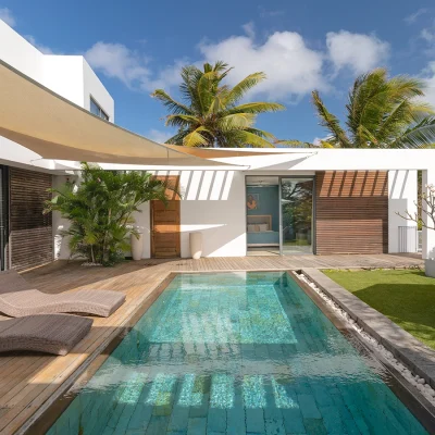 Courtyard pool surrounded by a secluded garden and deck with sunbathing chairs.