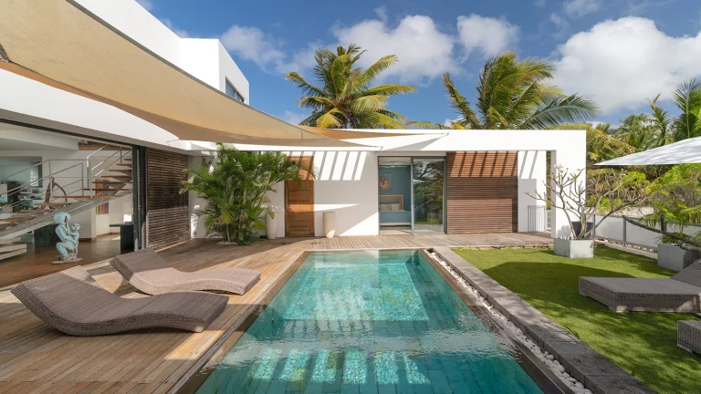 Courtyard pool surrounded by a secluded garden and deck with sunbathing chairs.