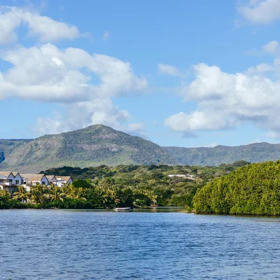 Meandering estuary with a cluster of villas on the shore and the Black River National Park mountain range in the distance.