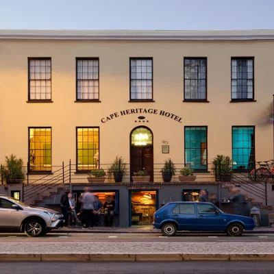 Historic boutique hotel with orange washed walls, sash windows and a double sided stair case leading you to the arched double wooden door entrance. Cape Heritage Hotel.