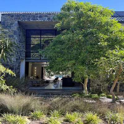 Pinebeach home set on two voluminous levels of polished white and exposed stone walls, tall glass industrial doors and windows with a luscious front garden.