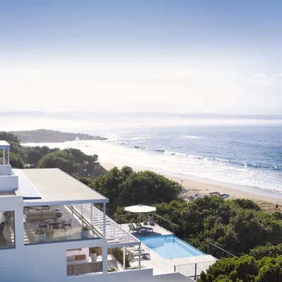 Modern three tier villa, Walkers Beach Villa with crisp white walls, an infinity swimming pool, three private patios with pergolas and panoramic views of Plettenberg Bay beach.