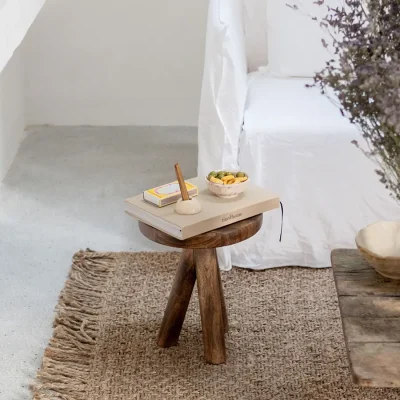 White epoxy floors warmed by a woven rug with a side table and white linen sofa in Casa Piana living room.