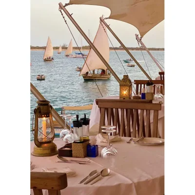 Peponi Hotel dining on with white linen tables set on the Indian Ocean scattered with traditional wooden dhows.