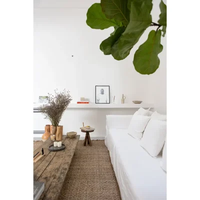 Serence white hue's reflecting in the walls, the floating shelf and large linen sofa that compliments the woven rug and rustic wooden coffee table in Casa Piana living room.