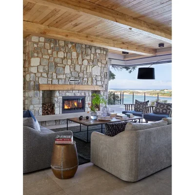 Covered verandah with contemporary outdoor lounge, a built in fireplace, and a view of the river and ocean.