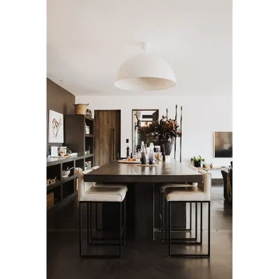 The Blogck kitchen with a sophisticated design reflective in the sleek charcoal counters and leather bar stools that are positioned below a large white ceiling light.