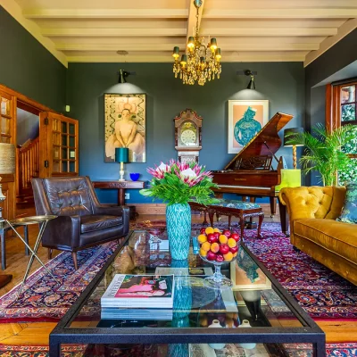 Colourful living room with opulent fireplace, piano and chandelier in House Nouveau.