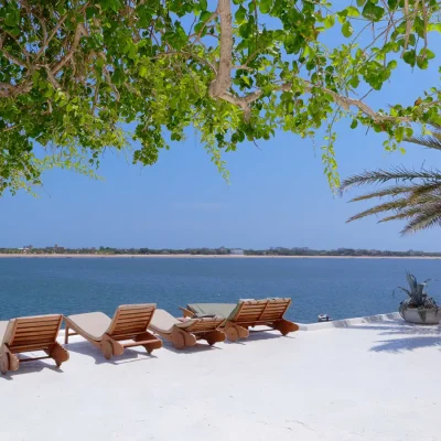 Expansive whitewashed deck with wooden sun loungers overlooking the calm ocean. Peponi Hotel.