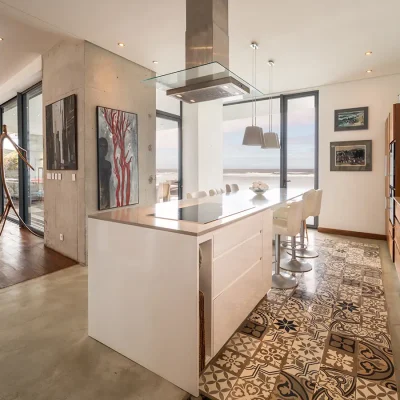 Open plan kitchen with an island that includes a built in stove top and surrounding bar stools, and overlooks the coral reef and lounge.