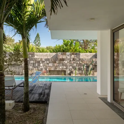 Wrap around verandah with view of palm trees, lap pool and contemporary stone wall. Villa De L'Ocean.