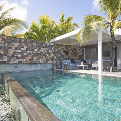 Private pool area with stone walls, and covered deck containing outdoor loungers.