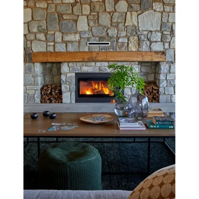 Contemporary stone wall with built in fireplace and wooden coffee table.