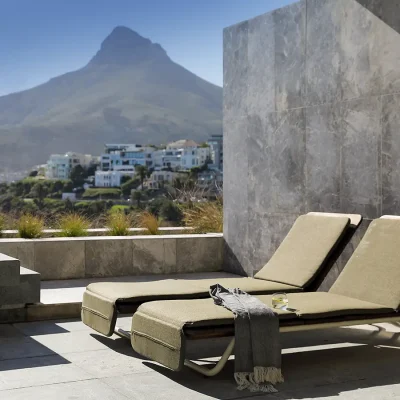 Two pool loungers positioned in the sunlight on the terrace of Ebb Tide, and overlooking the pool and views of Lion's Head.