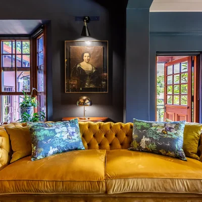 Large golden velvet sofa with backdrop of victorian portrait. House Nouveau.