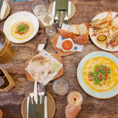 Dining table at Peponi Hotel set with an assortment of fresh bread, grilled prawns, dips and basted fish.