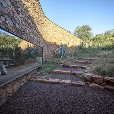 Contemporary stone wall structure with a large bay window that overlooks the wild garden at Witklipfontein eco lodge.