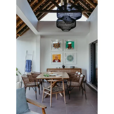 Wooden dining table on terrace of black River Penthouse with a white finish and protected by an elongated thatched roof.