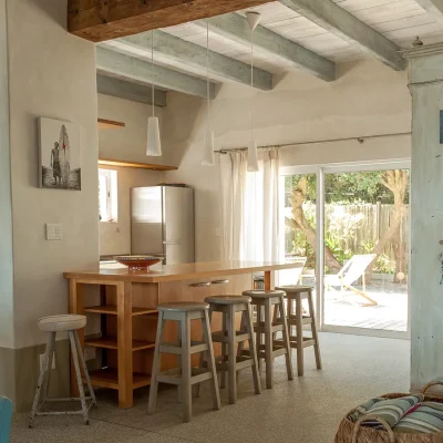 Pebbles tucked away kitchen with wrap around wooden cabinet and counter tops, and beige bar stools.