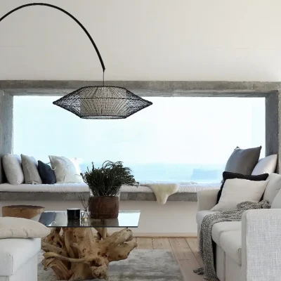 A beautifully curated lounge with a sun bed tucked into the vast bay window that provides expansive views of the ocean and reflects the calm of Feng Shui through the soft, white sofa and whitewashed walls.