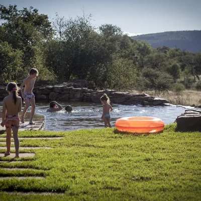 Children running around the garden and swimming in the natural swimming pool at Witklipfontein eco lodge.