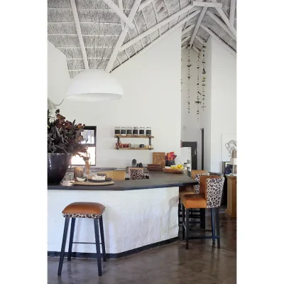 Wrap around kitchen with stone counter tops and leopard print bar stools with whitewashed walls and high ceilings.