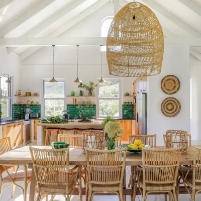 Natural hues of Banghoek Nature Reserve reflecting in the long wooden dining table and chairs, the green tiled kitchen walls and wooden cabinets, and the surrounding decor.