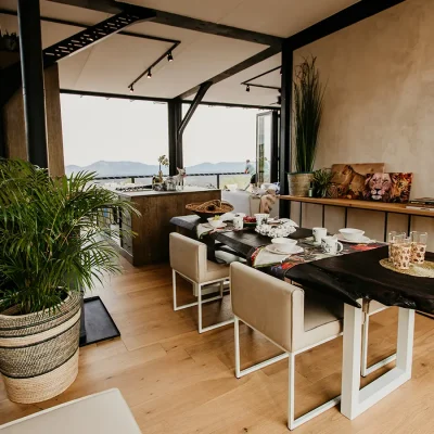 Carved wooden table with beige leather chairs, a side cabinet with lion prints and facing the kitchen island and distant views of the reserve.