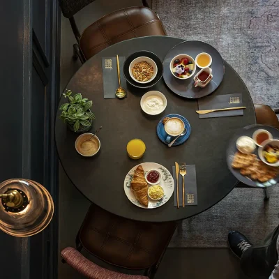 Breakfast served on a Black bistro dining table that compliments the charcoal walls with brown leather chairs and Persian rug. Labotessa Hotel.