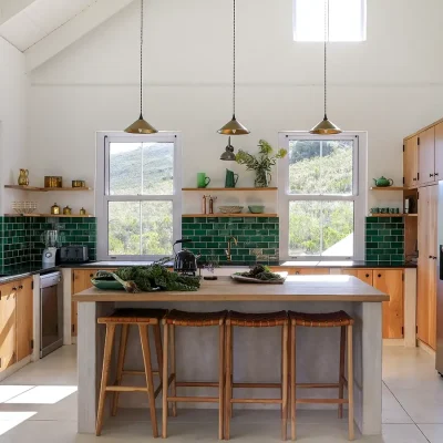 Buchubos Villa with a kitchen island and bar stools, green tiled walls and wooden floating shelves that match the wooden kitchen cabinets with granite tops.