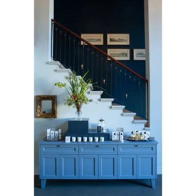 Labotessa Hotel entrance lobby with azure wooden cabinets and a white stair case with navy blue walls decorated in wall art.