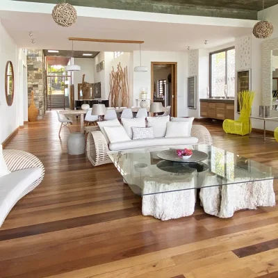 Open plan lounge and dining room with wooden floors, contemporary white couches and a glass coffee table with statement yellow armchairs.