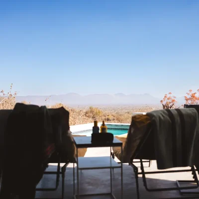 Panoramic views of the Limpopo bushveld and distant Waterberg mountains from the Blogck patio with two comfortable armchairs and a lengthy corner swimming pool.