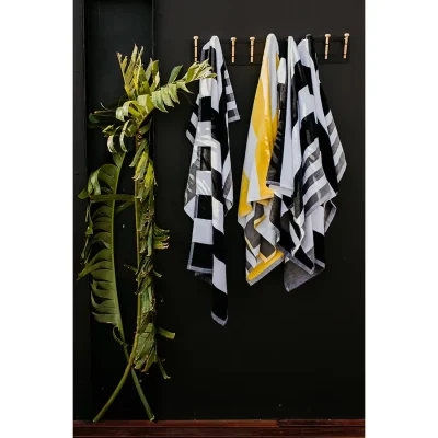 Black and yellow towels hanging on hooks against a charcoal black wall. The view.