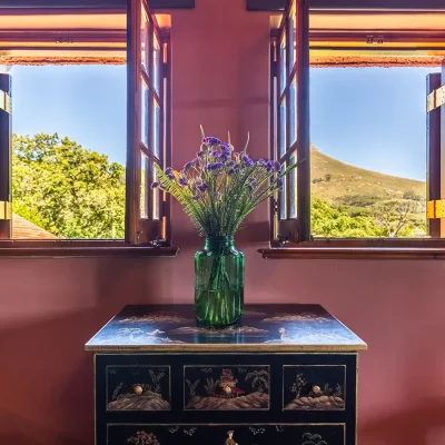 Detailed console against pink terracotta walls and open windows looking out to Signal Hill. House Nouveau.