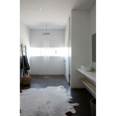 Open shower with natural light flooding in from a narrow bay window accentuating the calm white of Feng Shui and warmed by a decorative nguni skin.